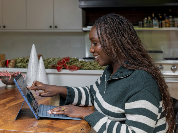 A woman works on a touch screen laptop in her home to illustrate understanding Facebook Ad Specs + Image Sizes