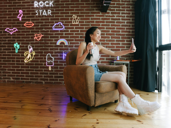 a woman sips a canned drink while filming herself with her phone, to illustrate getting more followers on TikTok