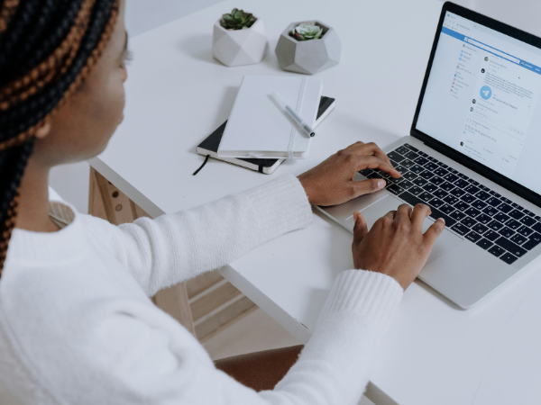 person in white long sleeve shirt using macbook air to illustrate scheduling a post on Facebook