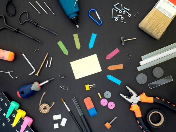 Flat lay of assorted tools and office supplies arranged in a circle on a black background to illustrate social media marketing tools