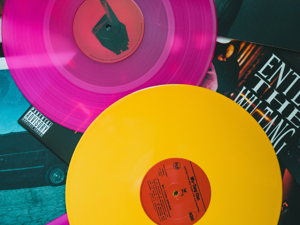 A bright pink and yellow record sit atop a pile of record covers to illustrate how to find trending sounds on TikTok
