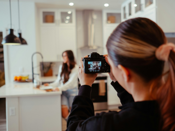 A woman films another woman cooking in a brightly lit kitchen to illustrate getting started with video marketing